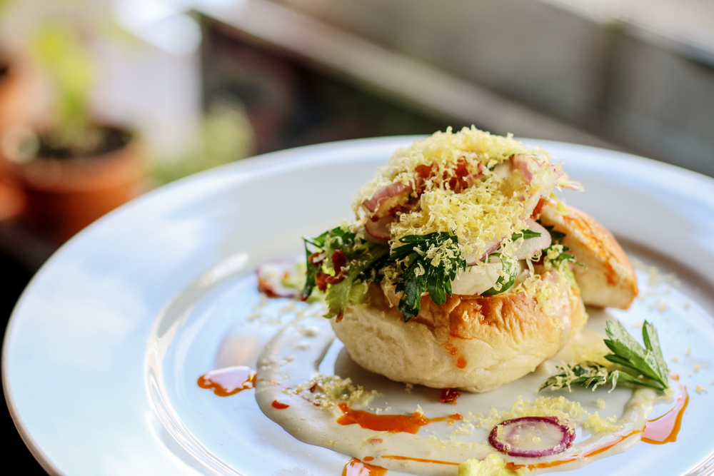 The Local's Egg in a Basket: a perfectly poached egg, with crispy Virginia ham, fresh micro greens, parmesan gravy and cured egg on a house baked Sally Lunn roll.