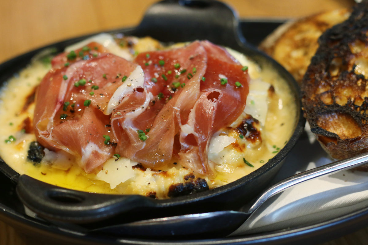 Wood oven baked eggs topped with prosciutto Bacon, sunny side up eggs and cheddar breakfast sandwich from restaurant Glass & Vine in the Grove. It's AMAZING! Click to read more or pin and save for later! Coral Gables | Miami | Coconut Grove | Florida
